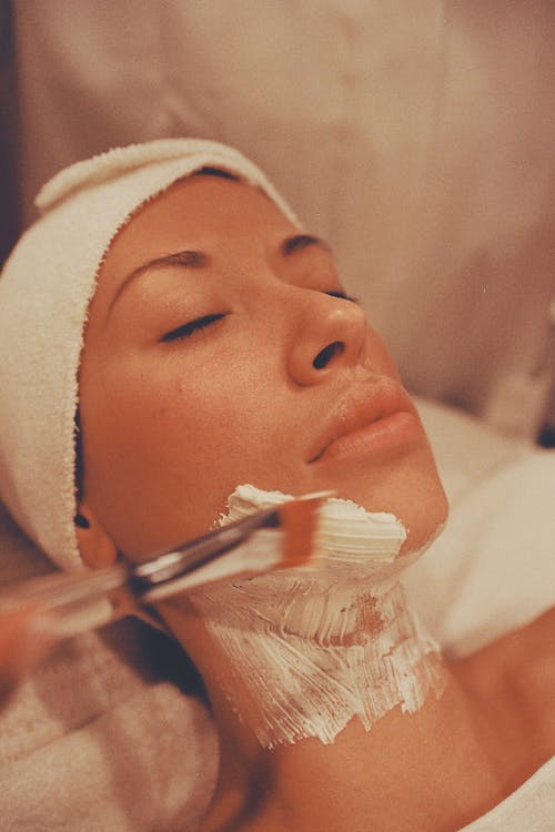 Woman receiving blue light facial treatment for acne