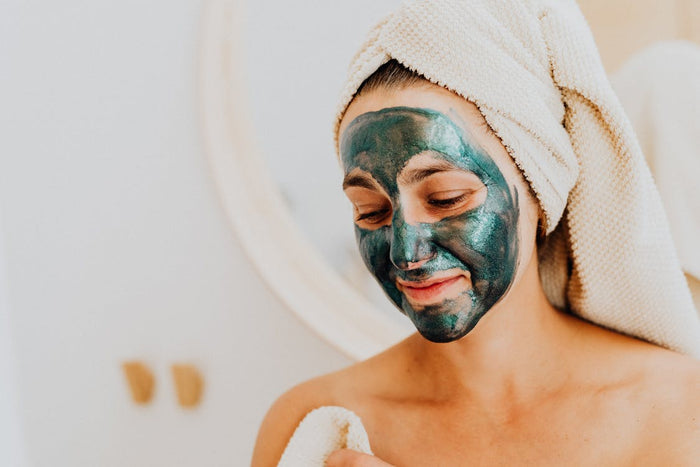 Woman relaxing with face mask skincare routine at home